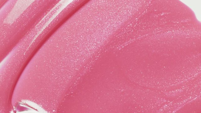 Close up of spatula smear pink shimmering lip gloss texture, satisfying texture stroke. Cosmetic product swatch background