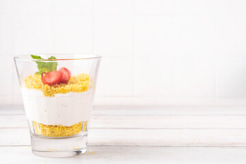 Classic cheesecake in glass, with fresh strawberry and golden cookie crumble