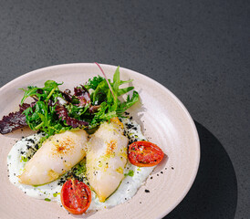 Delicate stuffed squid with salad and cherry tomatoes served on a plate
