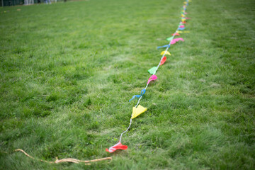 A ribbon with flags on the green grass. Festive ribbon on the lawn. Fencing of the territory for games.