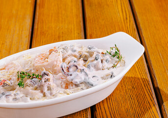 Shrimp and mushroom dish served in a white bowl on wooden table
