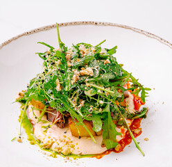 Fresh arugula salad with seasonal vegetables and nuts served on a plate
