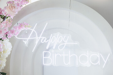Joyful birthday celebration adorned with elegant floral decorations and a glowing sign in a vibrant setting