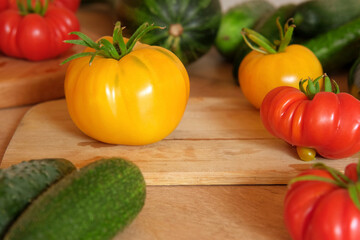 Fresh ripe big tomatoes, eggplant, veggies on a kitchen wooden workplace. Many raw vegetables background. Tomato, cucumbers. Cooker at home making a healthy veggie meal. Preparing vegetarian dish