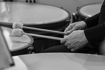 Hands of a musician playing the timpani in black and white