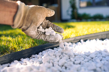 Filling a Garden Bed with White Pebbles and Lawn Background