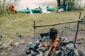 Tourist cooking camping food picnic on campfire kitchen, cauldron hang over fire