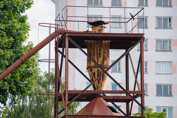 Rusty industrial structure stands against modern buildings in a