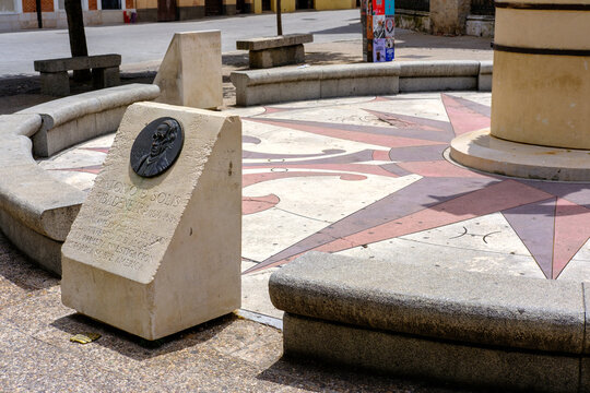 View of a compass rose design embedded in a plaza with stone benches and monuments under the bright sun, Alcala de Henares, Community of Madrid, Spain.