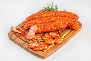 Spicy chorizo sausages with sliced pieces and paprika on wooden board