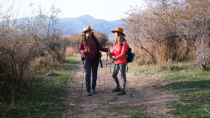Two female hikers stood on a dirt path to discuss the further route. The sisters travel together....