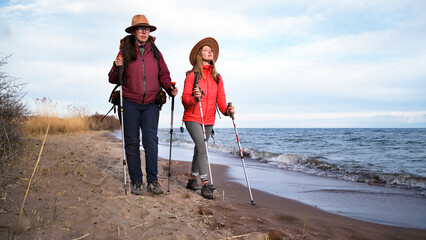 Independent travelers stroll along the wild beach. Two women in love are actively spending time on...