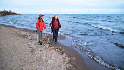 A couple of women in love are walking along the edge of the sea. Romantic walk along the wild beach. Two students are traveling together
