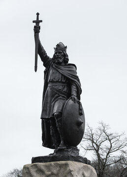 View of a bronze statue of King Alfred the Great stands proudly against a pale winter sky, clutching a sword and shield, Winchester, England, United Kingdom.