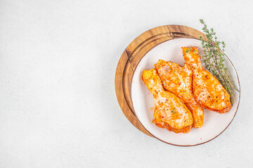Raw marinated chicken drumsticks with spices and herbs on white plate. top view. copy space