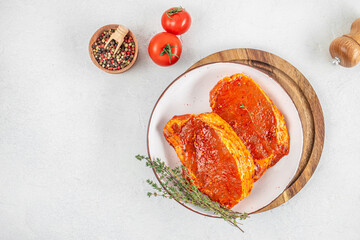 Raw marinated pork steaks with spices and herbs on white plate. top view. copy space