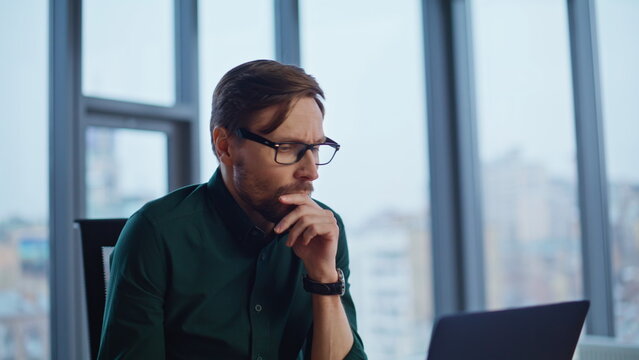 Shocked employee reading dismissal notice at laptop working at office closeup.