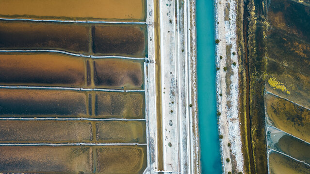 Aerial view of the contrasting earthy tones of salt ponds and the bright turquoise canal create a striking geometric pattern, Pag, Zadar County, Croatia.
