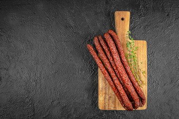 Dry cured sausages with herbs on wooden cutting board. top view. copy space