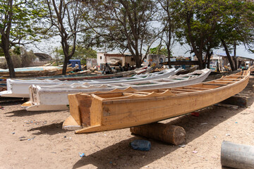Dakar, Senegal - 12 May 2025: View of wooden boats resting on the sandy ground at Plage de SoumbÃ©dioune, beneath the shade of trees, showcasing the craftsmanship and maritime culture.
