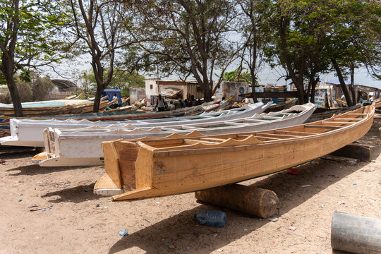 Dakar, Senegal - 12 May 2025: View of wooden boats resting on the sandy ground at Plage de SoumbÃ©dioune, beneath the shade of trees, showcasing the craftsmanship and maritime culture.