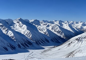 Naklejka premium A vast expanse of snow-capped mountain peaks stretches into a clear cerulean sky, showcasing dramatic mountain ranges and valleys.