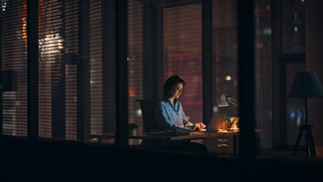 Night employee working startup at dark corporate office. Hardworking woman busy