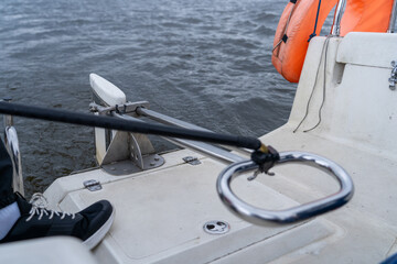 View from boat's transom across textured water, highlighting marine equipment like lifebuoy, safety ring, and nautical gear on grey day