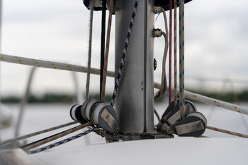 Close-up view of sailboat mast base with intricate rigging, multiple ropes, and pulley blocks on...