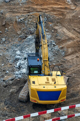High-angle view of powerful yellow tracked excavator, equipped with hydraulic hammer, positioned...