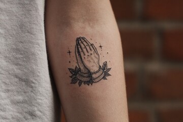 Obraz premium Tattoo of praying hands surrounded by leaves and stars, symbolizing hope, faith, and spirituality