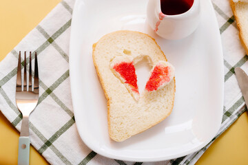 Romantic toast with heart cutout filled with red jam, symbol of affection and Valentine breakfast, creative food presentation.