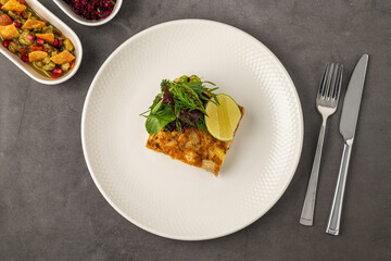 Spanish tortilla with potato and chicken, topped with fresh greens and lime