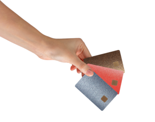 Hand holding three colorful credit cards with chip in metallic textures bronze, red, and silver.