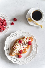 Trendy viral flat croissant on white plate, coffee. Delicious buttery thin croissant with fresh raspberry, cream. french breakfast. Crusty flat croissant recipe, bakery, cafe menu, copy space top view