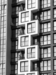 Close-up view of modern apartment facade with geometric balcony design and large glass windows.