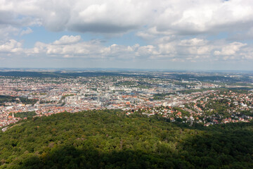 Aerial view of Stuttgart city and green forest on a sunny day with fluffy clouds