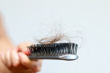 close-up image of a woman's hand holding a comb, with a focus on hair loss and care. hair loss...