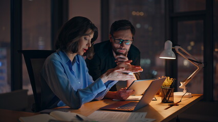 Businesswoman explaining project issues to man executive in night office closeup