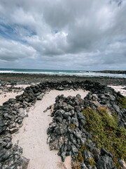 Unique rock formation along the shoreline with dramatic clouds above in a coastal setting
