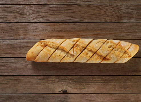 Baguette angeschnitten auf rustikalem mittelbraunem Fond