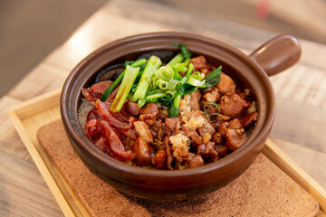 Traditional Hong Kong claypot rice served in earthenware bowl, topped with Chinese sausage, marinated chicken, shiitake mushrooms, and green onions