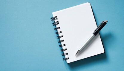 Open spiral notebook with blank pages and a pen on a blue background for note-taking