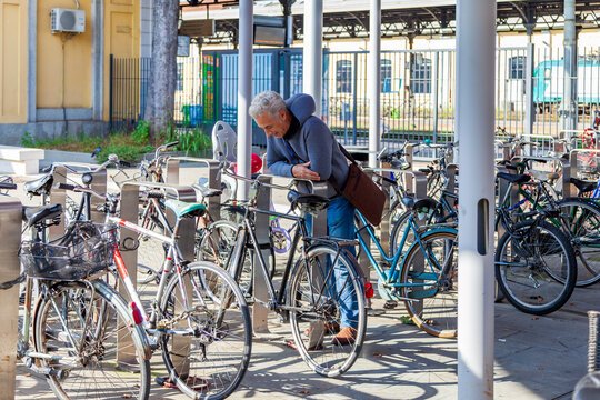 A middle-aged man with gray hair looking for his bicycle in the middle of a bike parking lot - Powered by Adobe