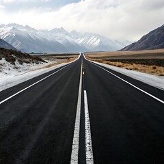 Fototapeta premium Empty asphalt road stretching towards snow capped mountains under a cloudy sky