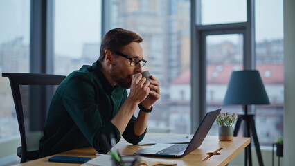 Relaxed employee drinking coffee at workplace taking break closeup. Smiling man