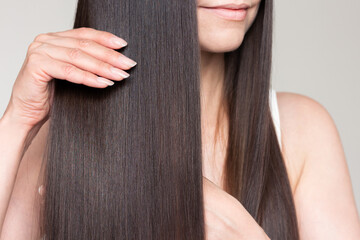 Young caucasian beautiful brunette woman with smooth shiny brown and straight long hair after keratin straightening.