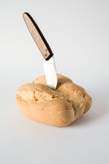 Pocket knife stuck in a loaf of bread on a white background