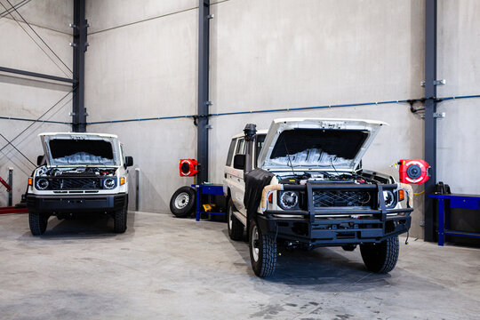 Utility vehicles with bonnets open parked inside workshop