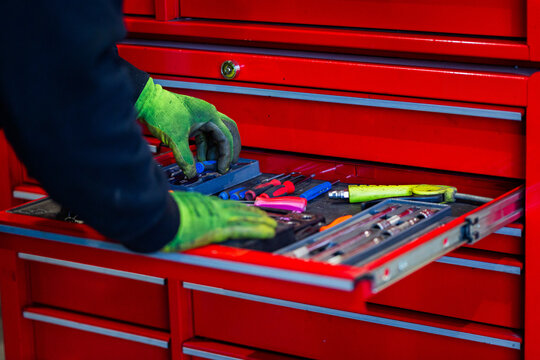 Mechanics hand wearing gloves getting tools from the red tool chest